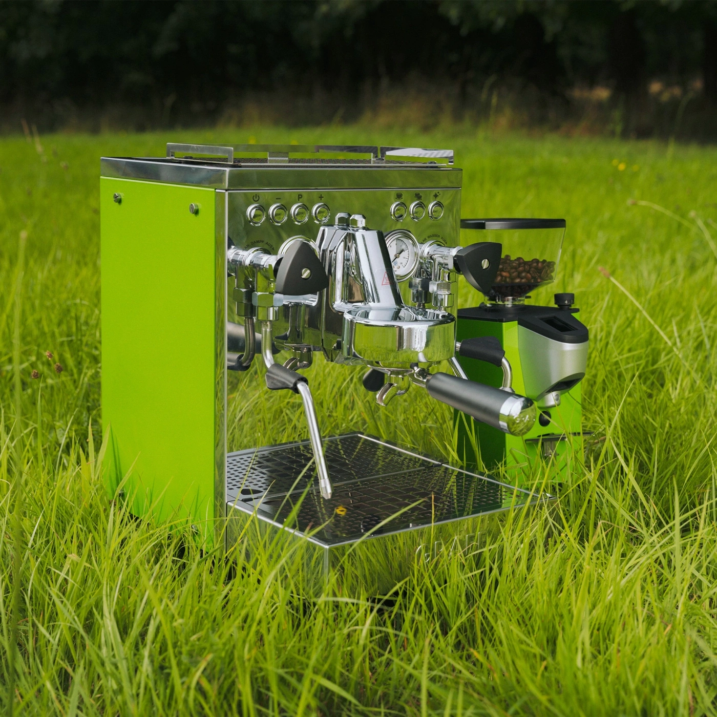 Eine grüne Espressomaschine mit Kaffeemühle im Gras.