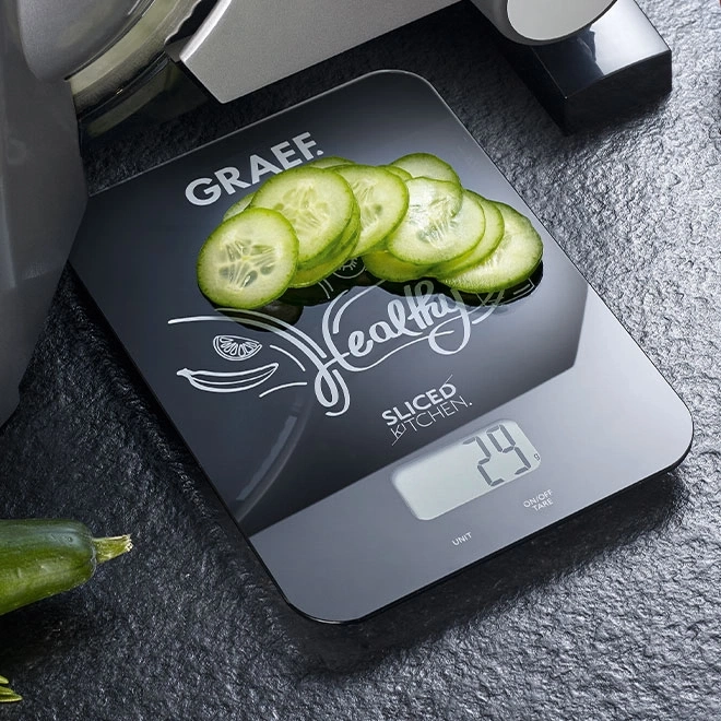 Waage mit Gurkenscheiben, zeigt 29g, 'Healthy Sliced Kitchen' Schriftzug.