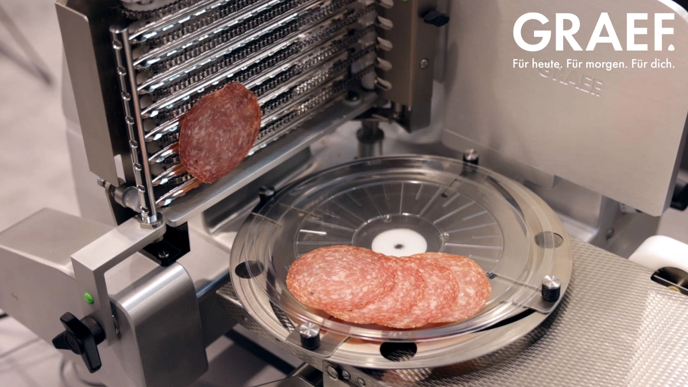 Wurstmaschine schneidet Salami. Graef-Logo. Für heute, für morgen, für dich.