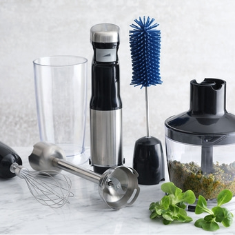 Küchenutensilien: Stabmixer, Becher, Quirl, Bürste, Gemüse, auf Marmor