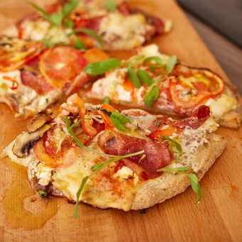 Gros plan sur une pizza aux tomates, au fromage et aux herbes sur une planche de bois