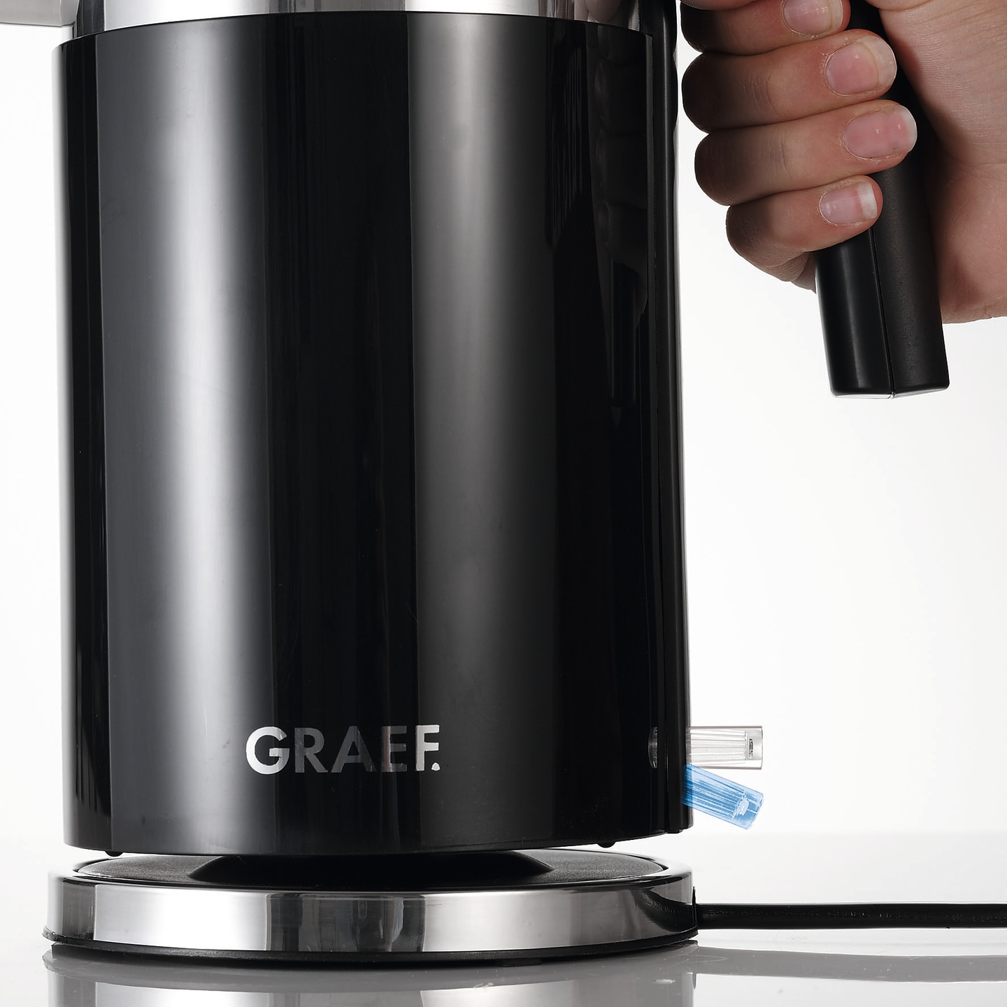 Bouilloire noire avec main et logo GRAEF sur fond blanc.