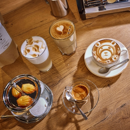 Kaffee-Kunst mit Gebäck auf einem Holztisch. Latte Art, Espresso.