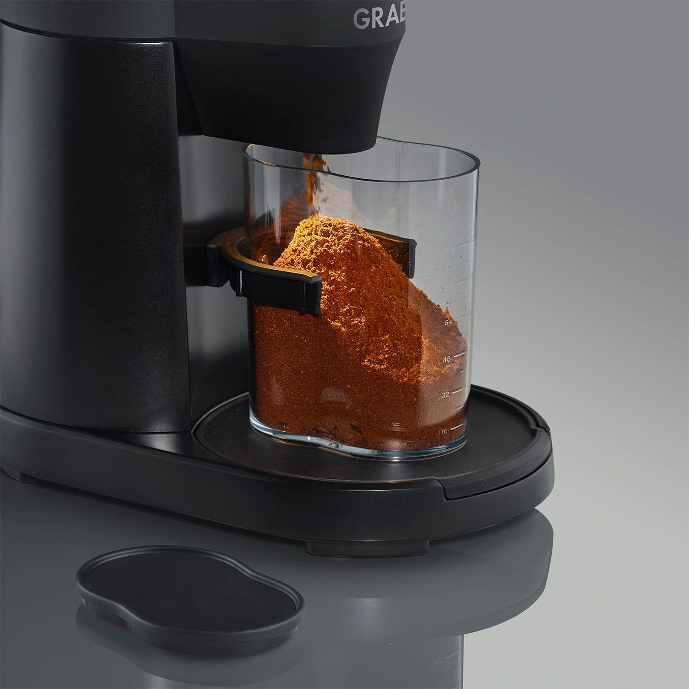 Kaffeemühle mit Glasbehälter, gefüllt mit Kaffeepulver, schwarzes Design, Detailaufnahme