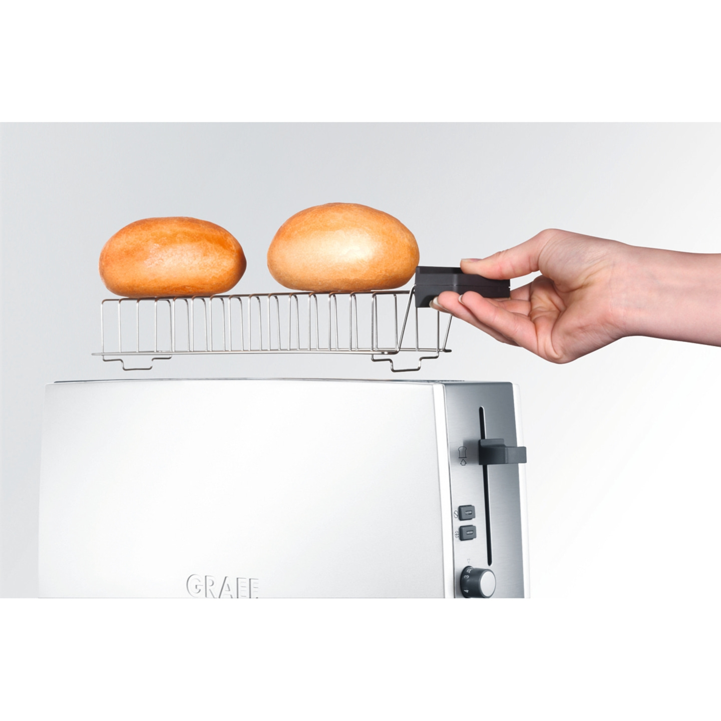 Toaster with buns and hand operating it, white background, Graef brand visible