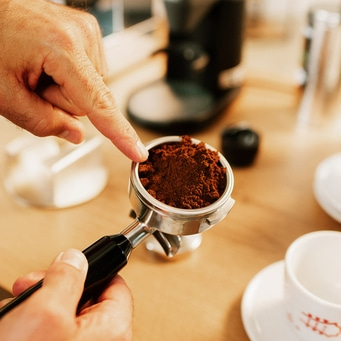 Mann zeigt mit Finger auf Siebträger mit Kaffeemehl