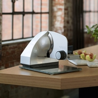 Ein silberner Graef-Schneidemaschine auf einem Holztisch mit Melonenstücken.