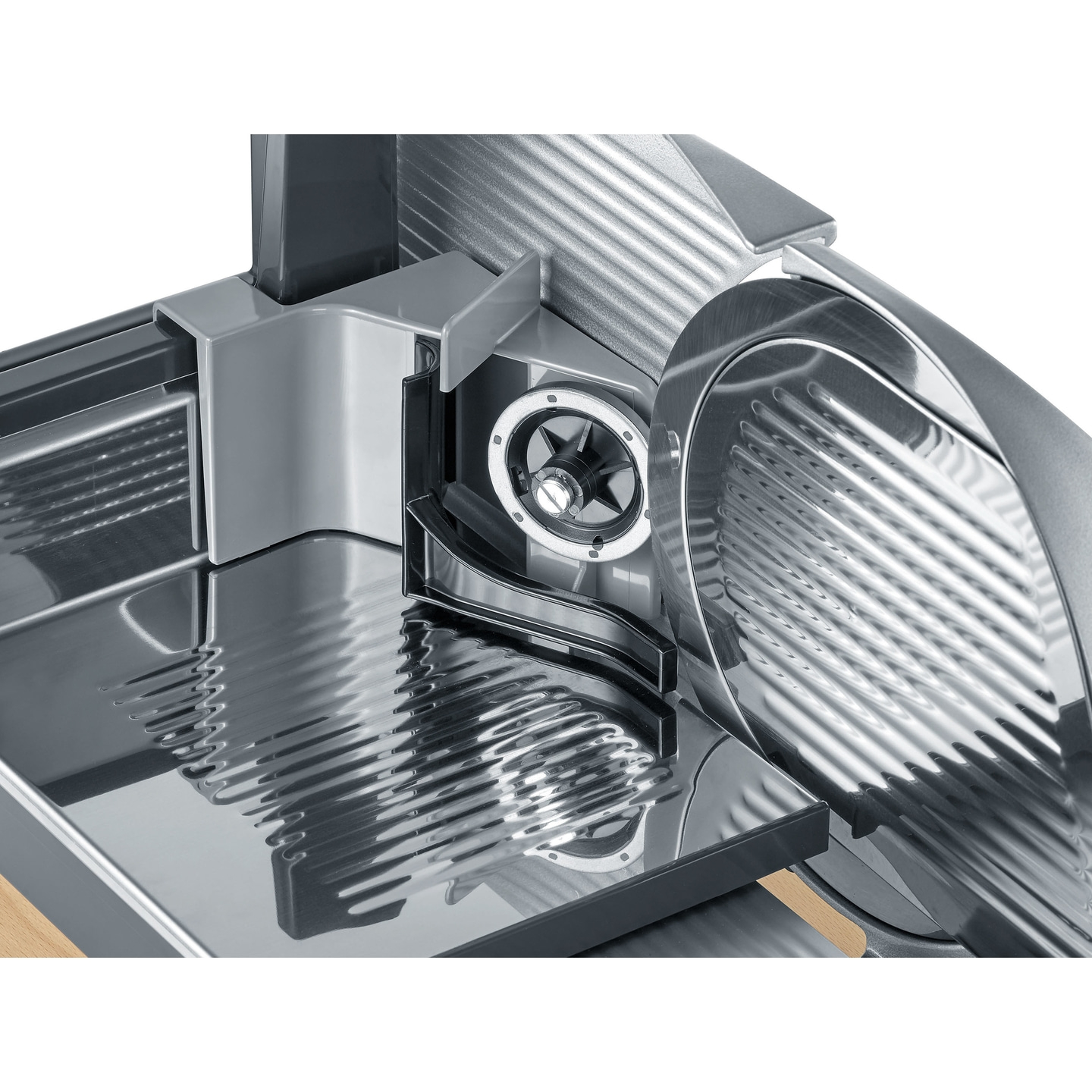 Close-up of a silver meat slicer with a wooden base and detailed view