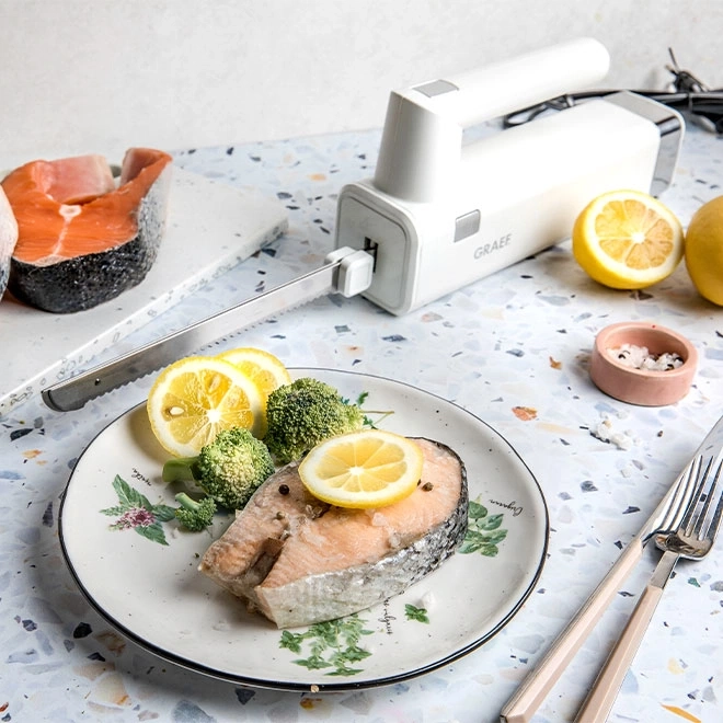 Lachsfilet mit Zitrone und Brokkoli, serviert mit Messer und Gabel.