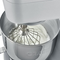 Close-up of a stand mixer whisking cream, shiny metal, kitchen appliance