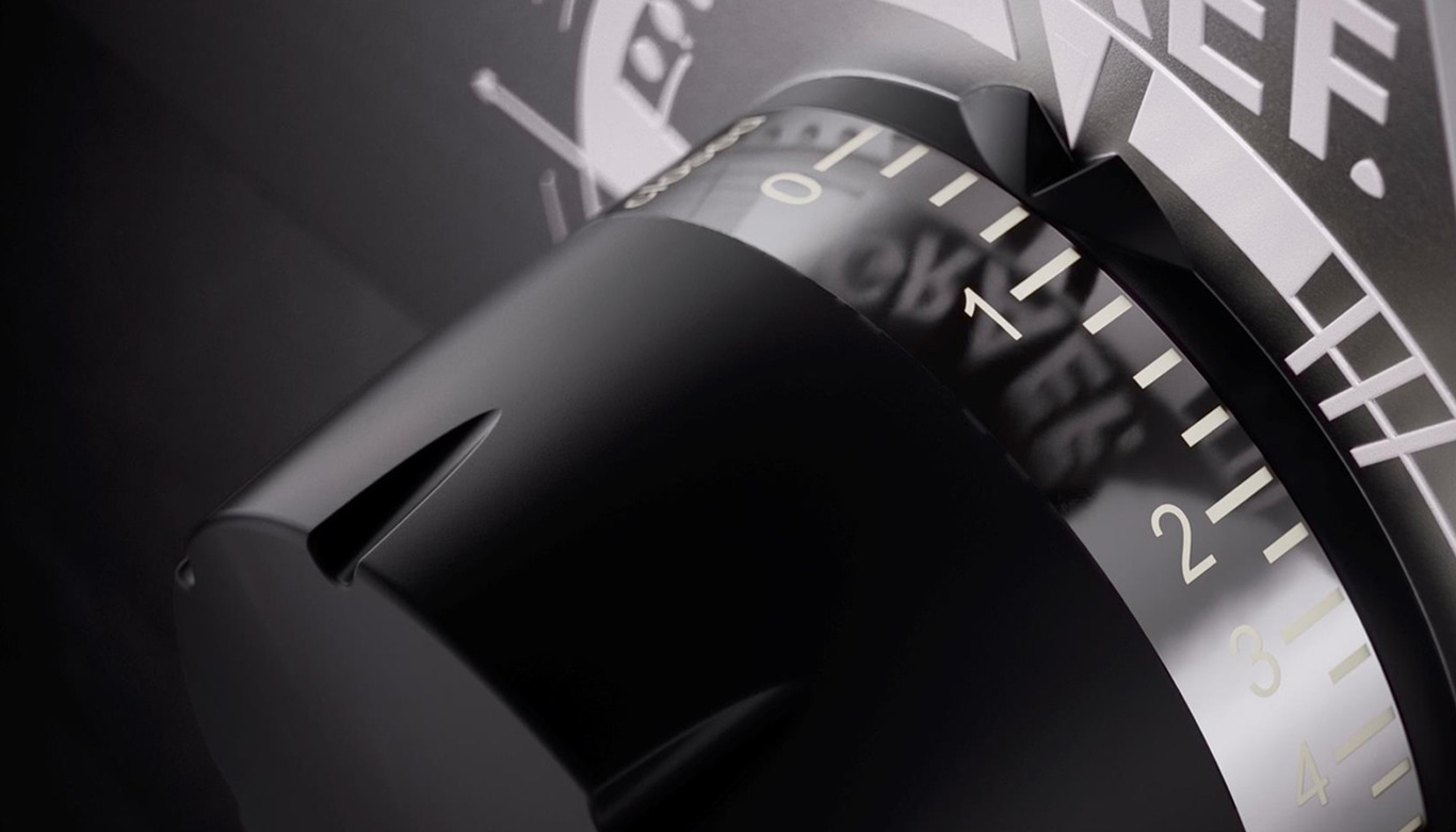 Nahaufnahme eines schwarzen Zifferblatts mit weißen Zahlen und Markierungen, Detailaufnahme