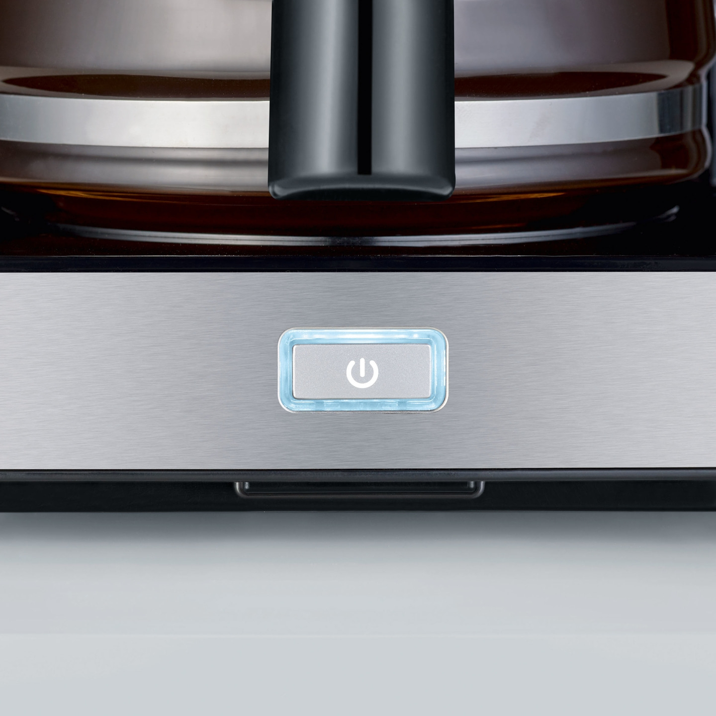 Close-up of a coffee machine control panel with power button and blue light
