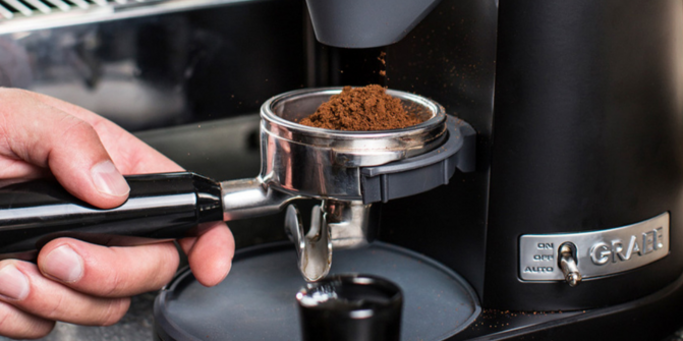Kaffeemaschine mit frisch gemahlenem Kaffee, der in den Filter fällt.