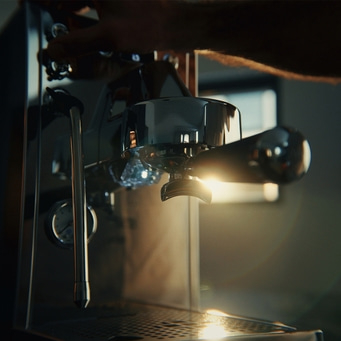 Nahaufnahme von Siebträgermaschine, Sonnenstrahlen im Hintergrund