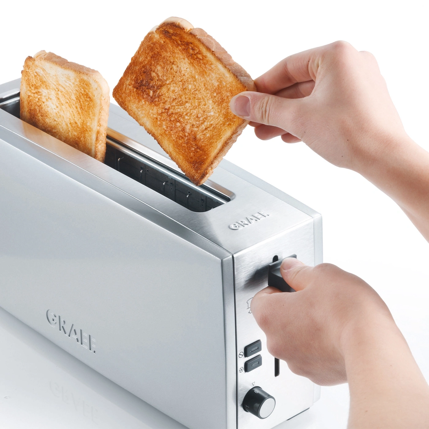 Toast wird aus einem Toaster genommen, der von einer Person bedient wird.