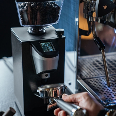 Coffee grinder with beans and portafilter, close-up shot, hand holding