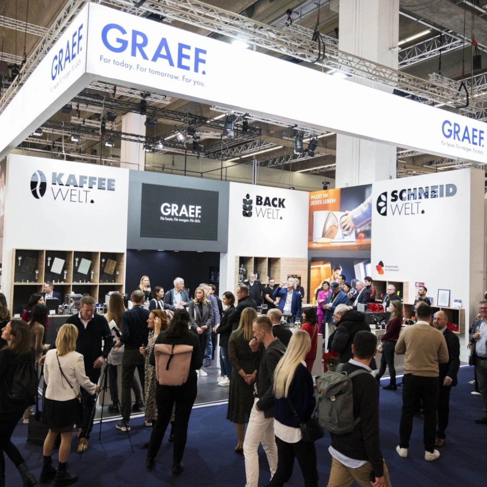 Messe-Stand mit vielen Menschen, GRAEF-Logo, Kaffee- und Backwelt.