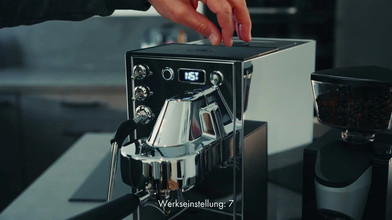 Eine Person bedient eine Kaffeemaschine mit Mühle.