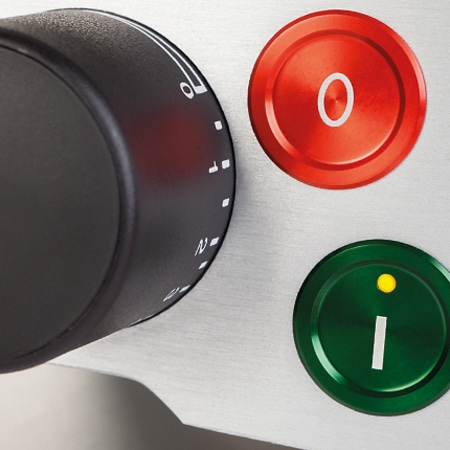 Schwarzer Drehknopf, rote und grüne Knöpfe mit Symbolen und Ziffern auf Metalloberfläche.