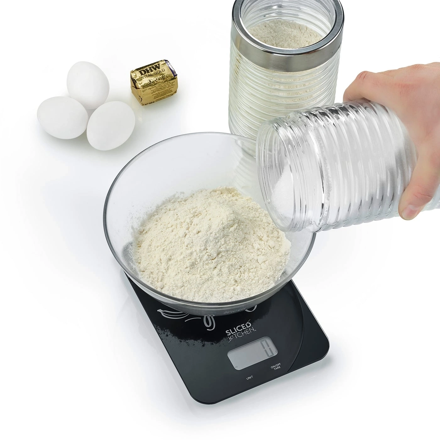 Zutaten für Kuchen: Eier, Butter, Mehl, Zucker, Waage, Glas, Hand.