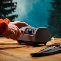 Mann schärft Messer auf elektrischem Schärfer im Wald