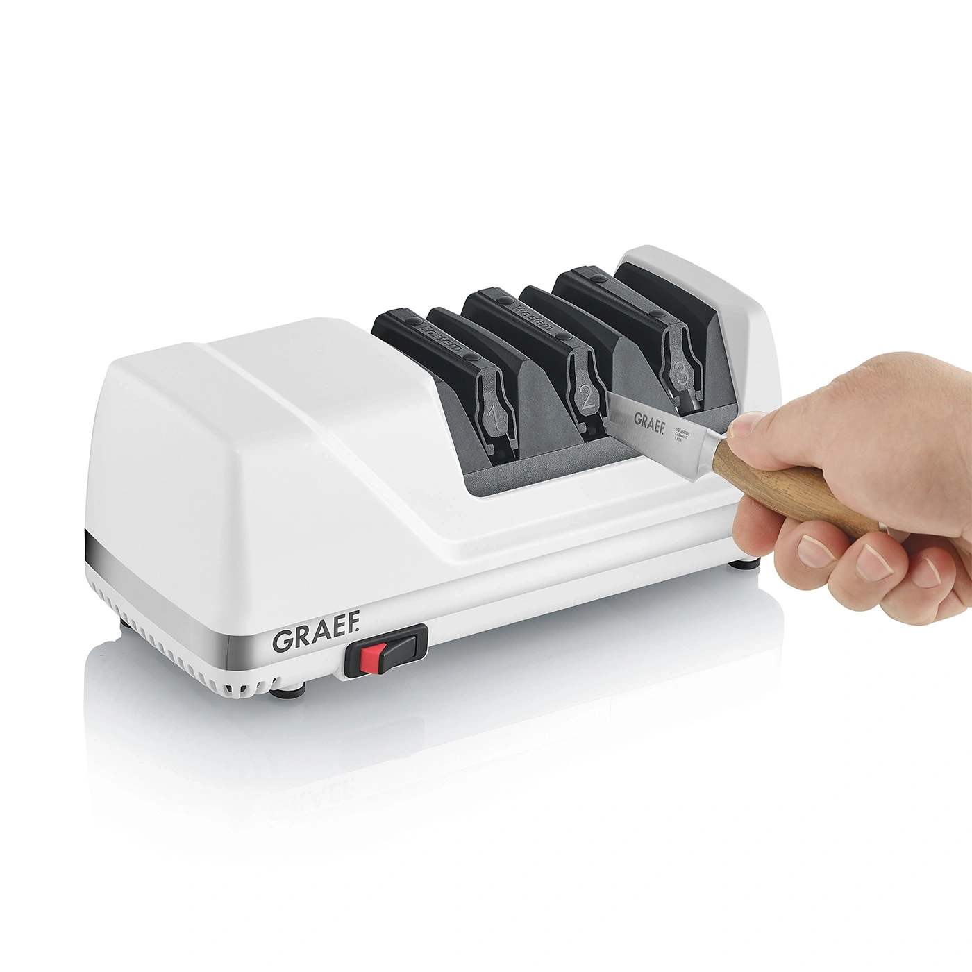 Ein weißes elektrisches Messerschärfgerät von Graef mit einem Messer, das von einer Hand eingeführt wird.