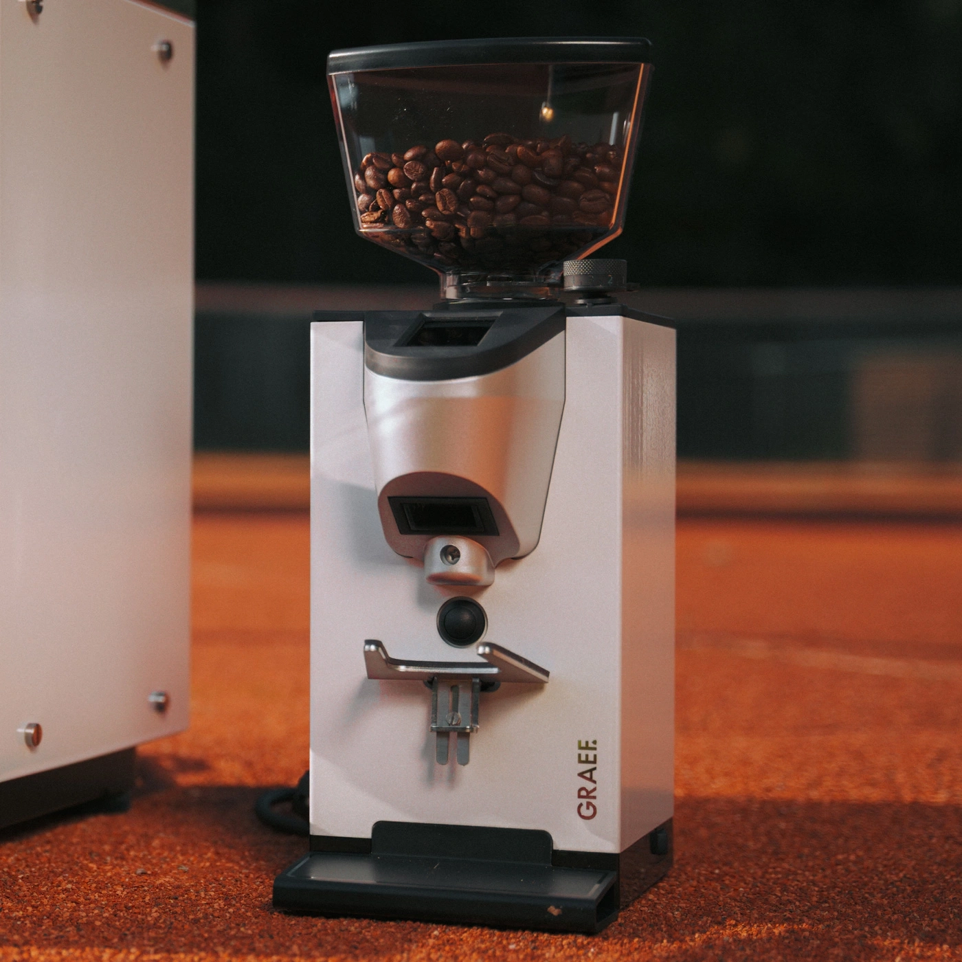 Kaffeemühle Graef auf orangefarbenem Untergrund mit Kaffeebohnen im Trichter.