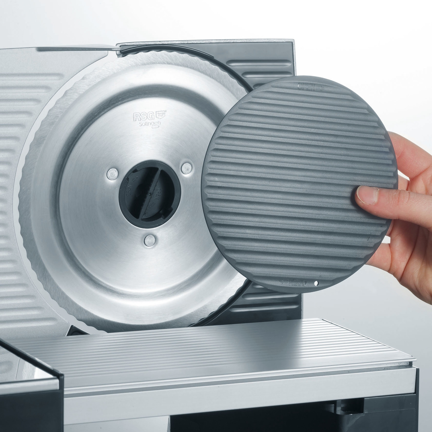 Close-up of a meat slicer with a protective guard and blade