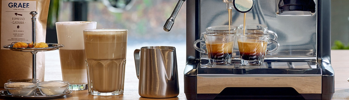 Machine à café avec café, verres et pâtisseries sur une table en bois.