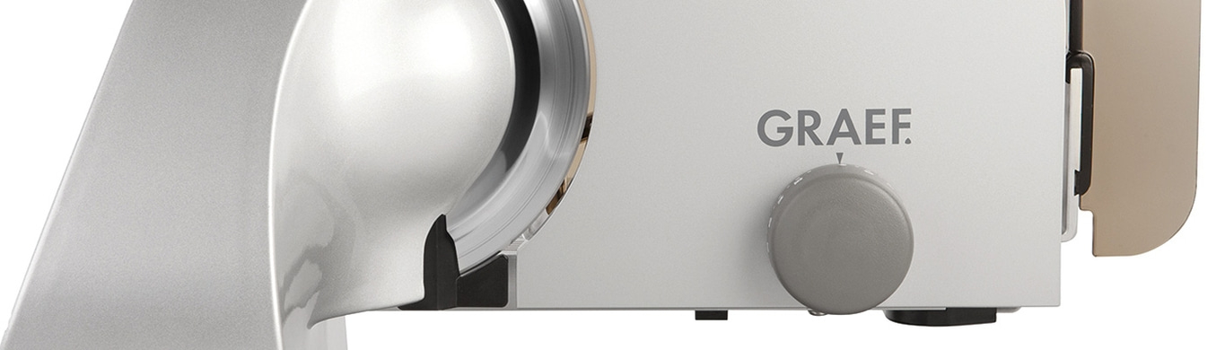 Close-up of a silver meat slicer with the brand name GRAEF on it.