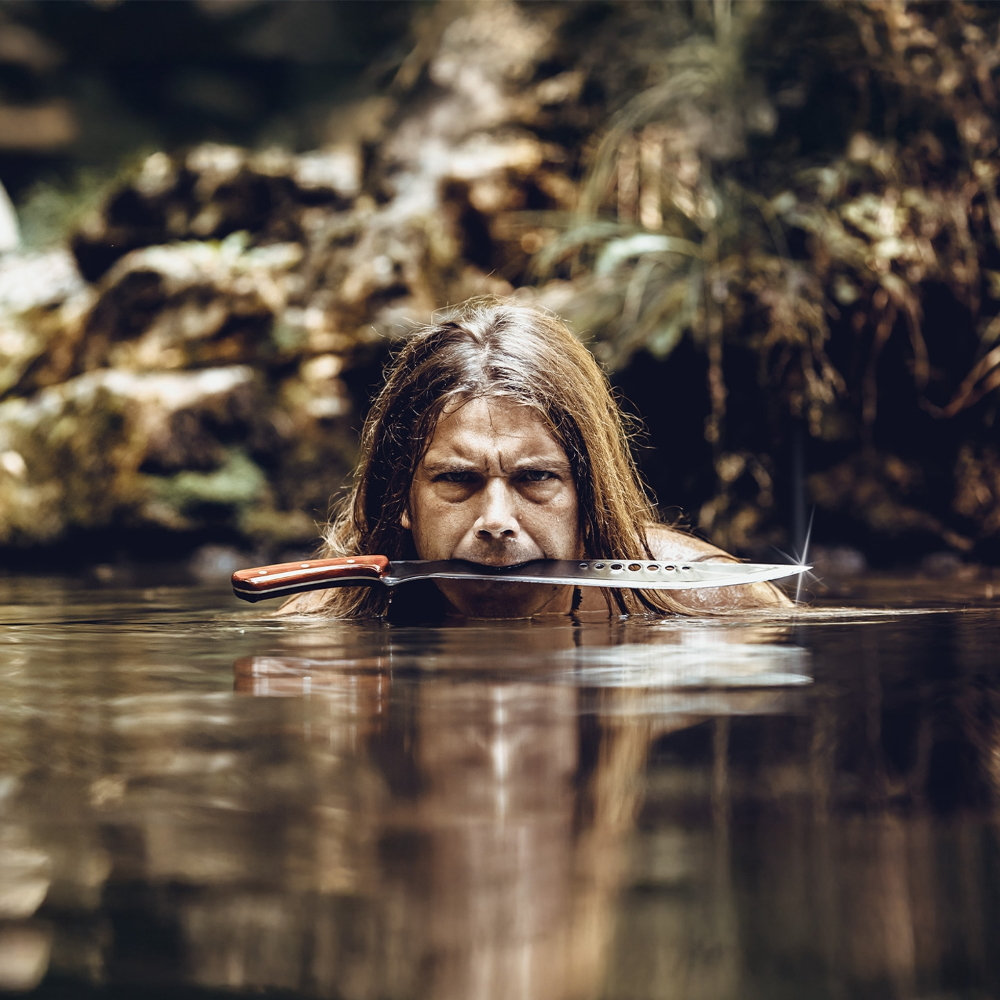 Mann mit Messer im Mund im Wasser