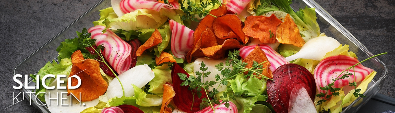 Insalata con patatine di verdure, barbabietole ed erbe aromatiche in un contenitore trasparente.