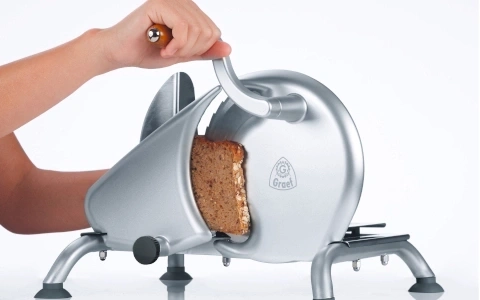 Eine Person schneidet Brot mit einer Brotschneidemaschine. Nahaufnahme.