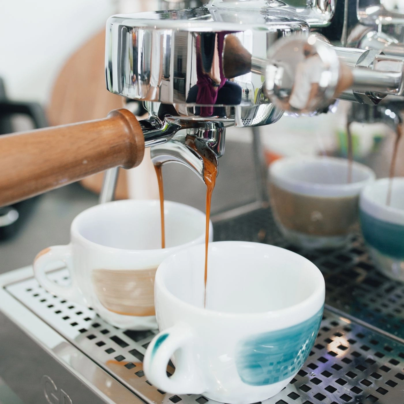 Kaffee wird in Tassen gegossen, die von einer Espressomaschine zubereitet werden.
