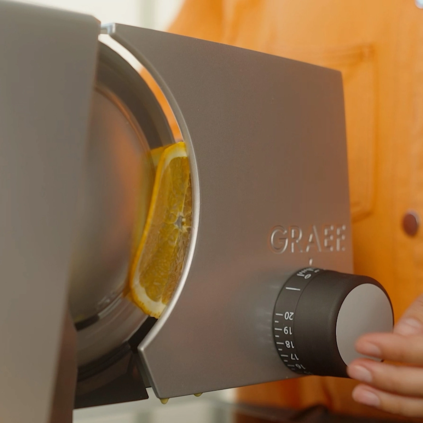 Eine Scheibe Orange wird in einer Graef-Schneidemaschine geschnitten.