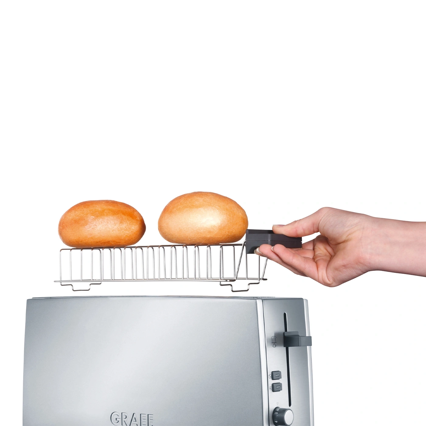 Toaster mit Brötchenaufsatz und zwei Brötchen, die von einer Hand gehalten werden.