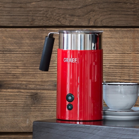 Montalatte rosso con tazza su superficie in legno. Logo GRAEF visibile.