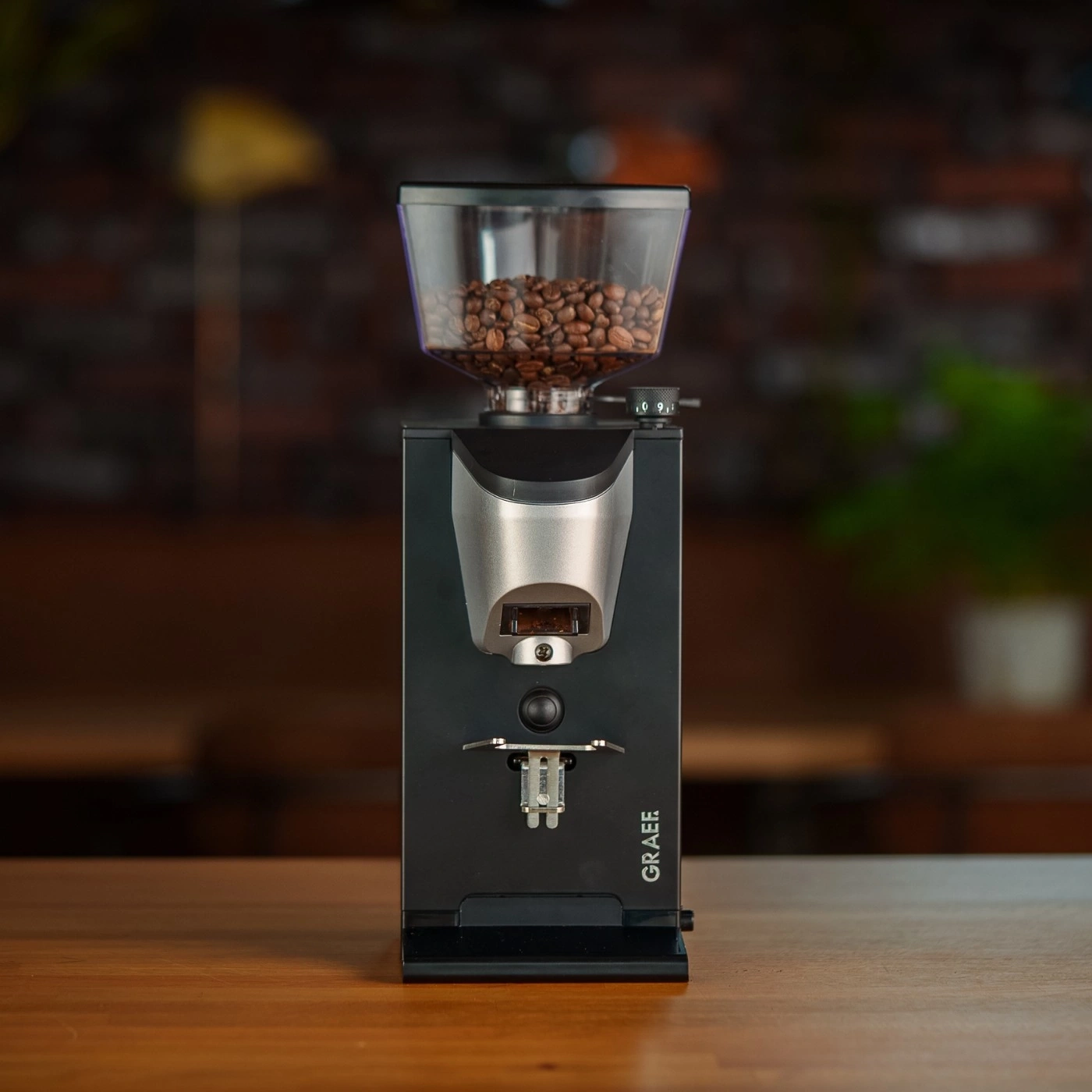 Kaffeemühle mit Bohnen auf einem Holztisch, GRAEF-Logo.