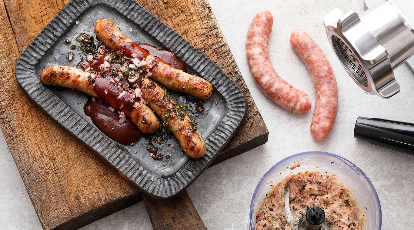 Grilled sausages on a plate with sauce and ingredients, close-up shot.