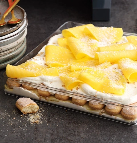 Dessert mit Mango, Sahne und Löffelbiskuits in einer Glasform