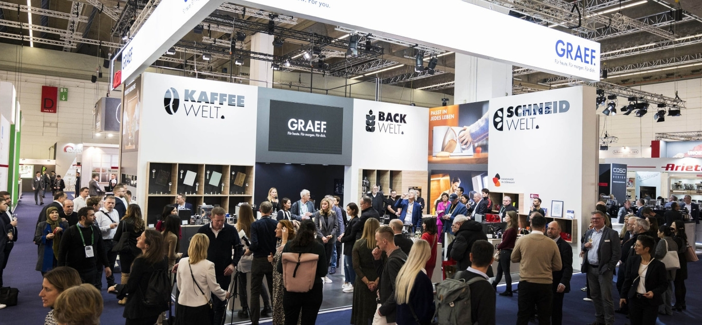 Messe-Stand mit vielen Menschen, Kaffee, Backen und Schneiden.