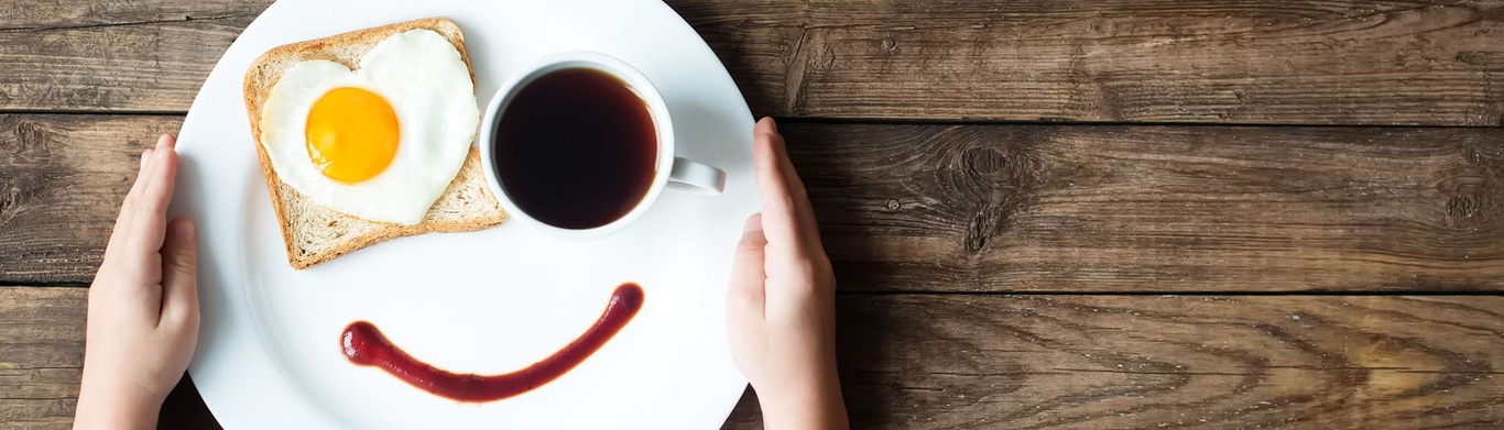 Assiette de petit-déjeuner avec œuf au plat, café et visage de ketchup sur bois
