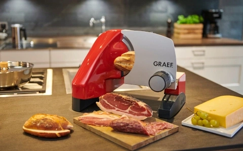 Aufschnittmaschine mit Brot, Fleisch und Käse auf einer Küchenarbeitsplatte.