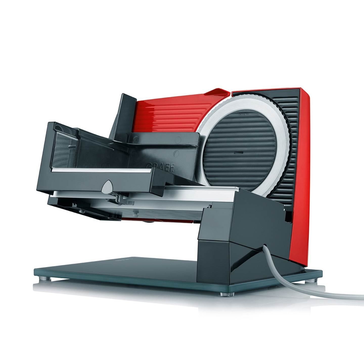 Red and black meat slicer on glass plate with a cable attached