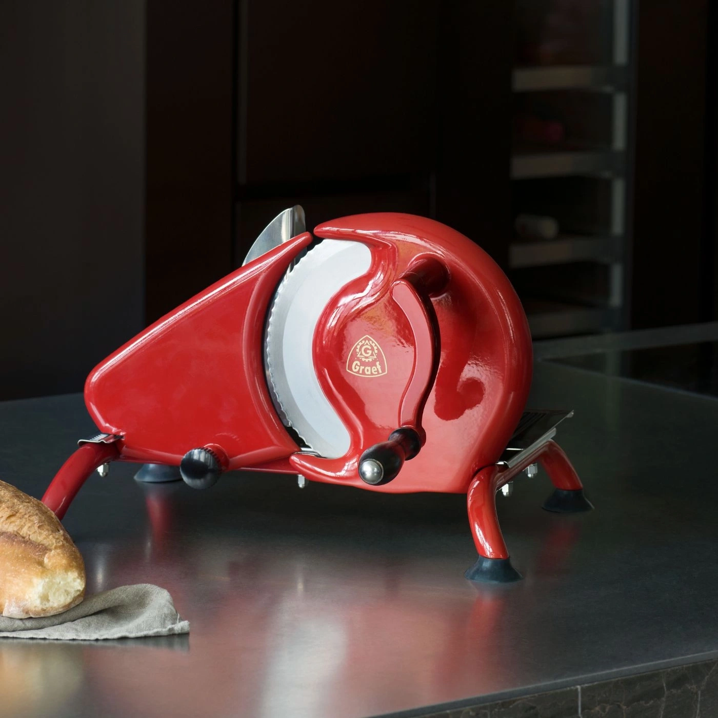 Rote Aufschnittmaschine mit Brot auf einer dunklen Oberfläche.