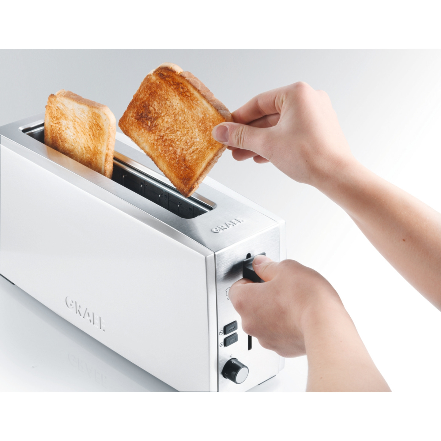 Toaster with toast, hands operating toaster, close-up, white background, breakfast
