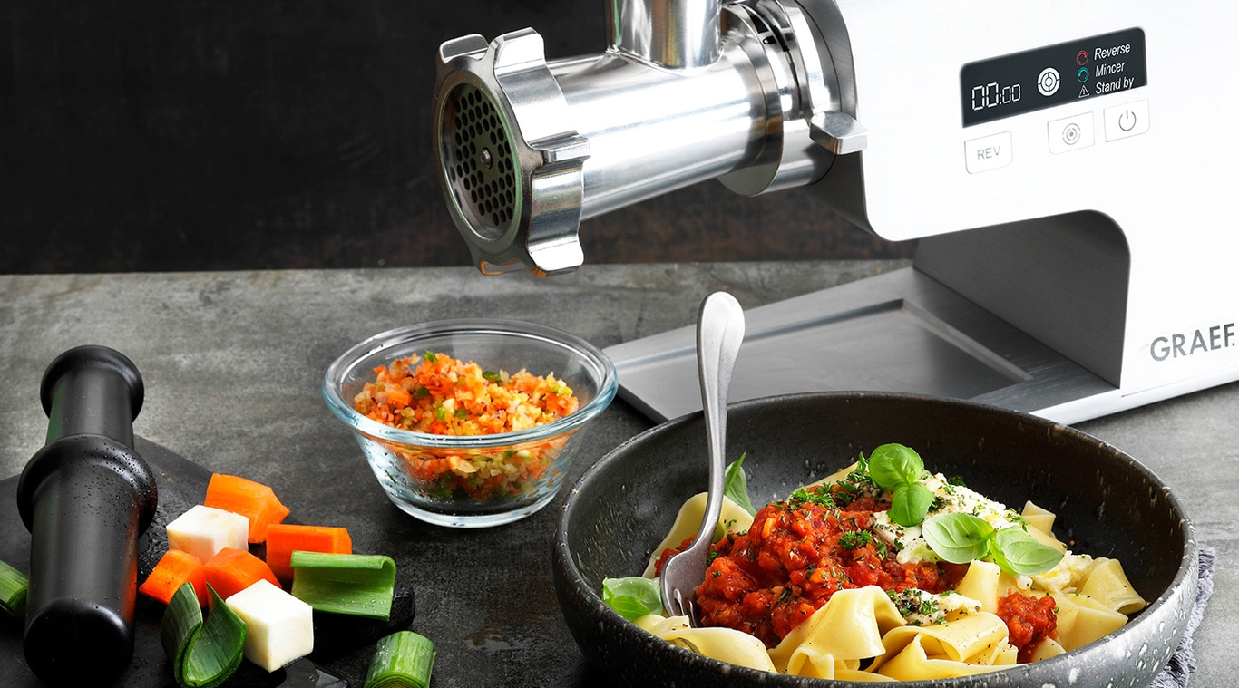 Meat grinder with vegetables and pasta. Cooking and food preparation concept.