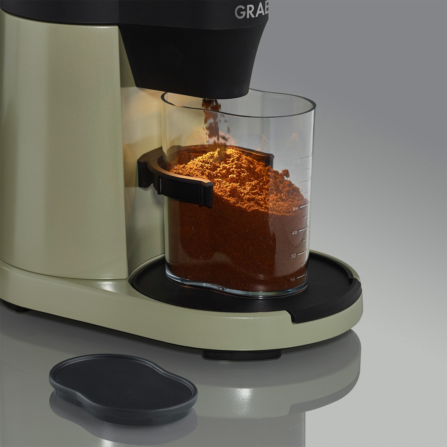 Coffee grinder, coffee powder, glass container, coffee preparation, kitchen appliance, coffee machine, grinding process, coffee beans, freshly ground