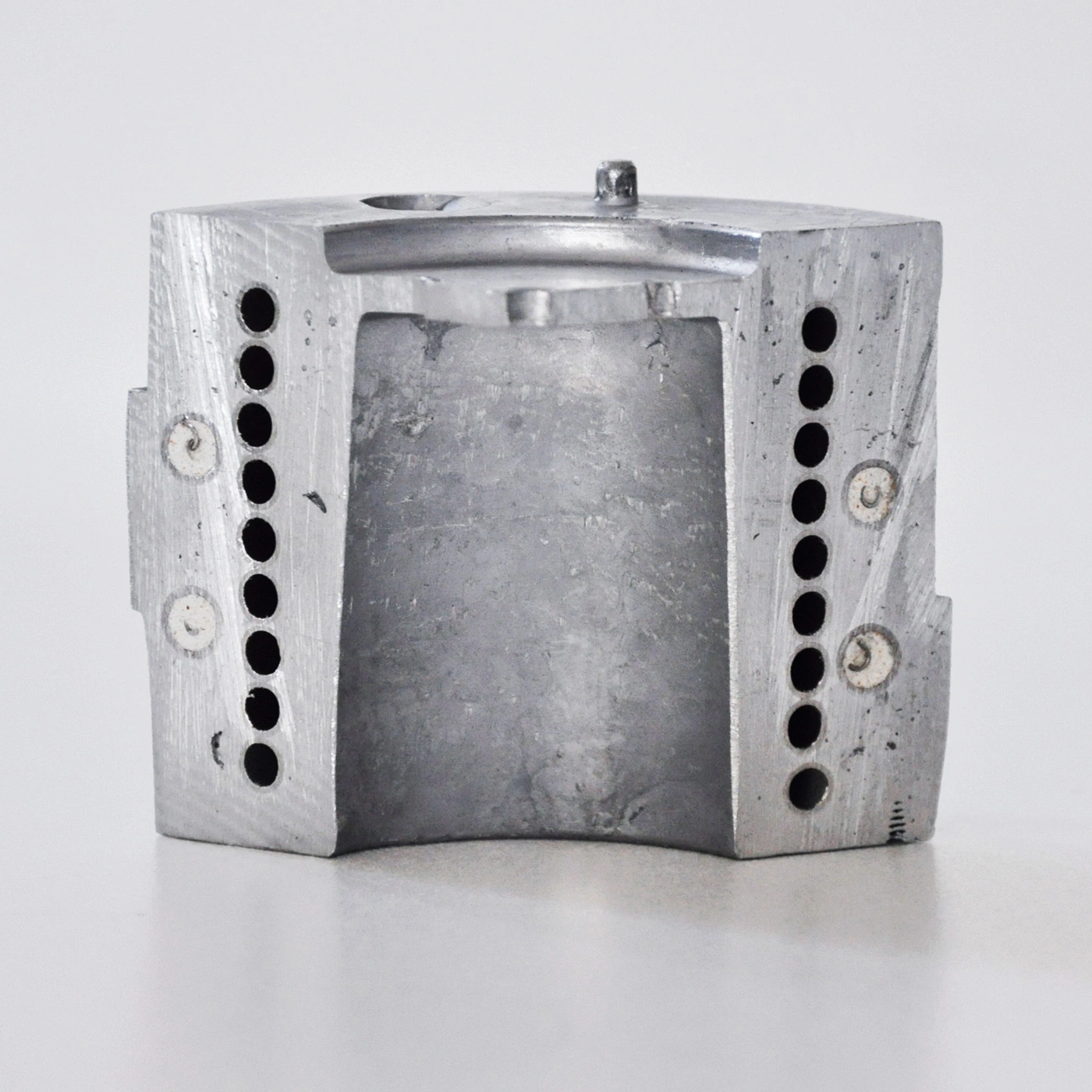 Metallblock mit Löchern und einem Loch in der Mitte, grau