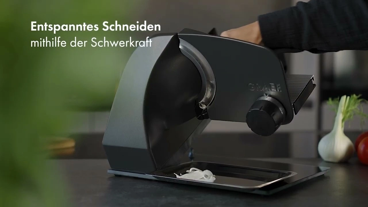 Schneidemaschine, die Gemüse schneidet, mit dem Text 'Entspanntes Schneiden mithilfe der Schwerkraft'.